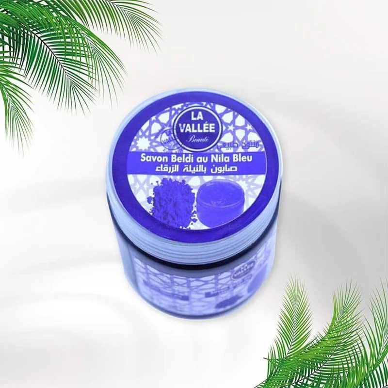 El Jabón Beldi con Nila Azul es un producto tradicional marroquí conocido por sus propiedades exfoliantes y regeneradoras. Este jabón combina la riqueza del jabón negro beldi con el polvo de nila azul, ofreciendo un cuidado completo para la piel. Características Principales Ingredientes Naturales: Elaborado con aceite de oliva y enriquecido con polvo de nila azul, un mineral natural que aporta luminosidad a la piel. Libre de químicos agresivos, respetando la tradición artesanal. Propiedades Exfoliantes: Ayuda a eliminar células muertas y suavizar asperezas, dejando la piel sedosa y renovada. Efecto Iluminador: El polvo de nila azul contribuye a blanquear y unificar el tono de la piel, aportando un aspecto radiante. Modo de Uso Aplicar sobre la piel húmeda, cubriendo todo el cuerpo. Dejar actuar de 5 a 10 minutos para que sus ingredientes penetren. Enjuagar y exfoliar con un guante kessa para mejores resultados. Este jabón es ideal para quienes buscan un cuidado corporal profundo y natural.